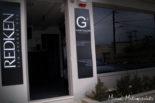 Η πρόσοψη του G2 Hair Salon, με την κάθετη πινακίδα και το πάνελ Redken